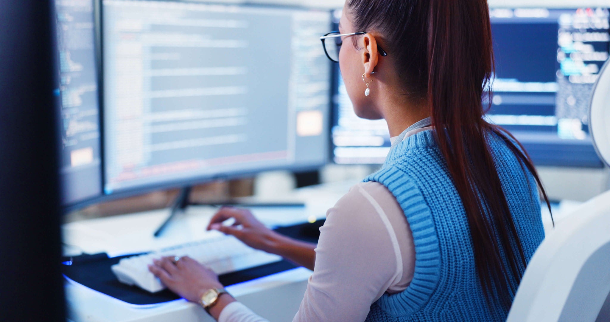 woman typing in front of a desktop monitor