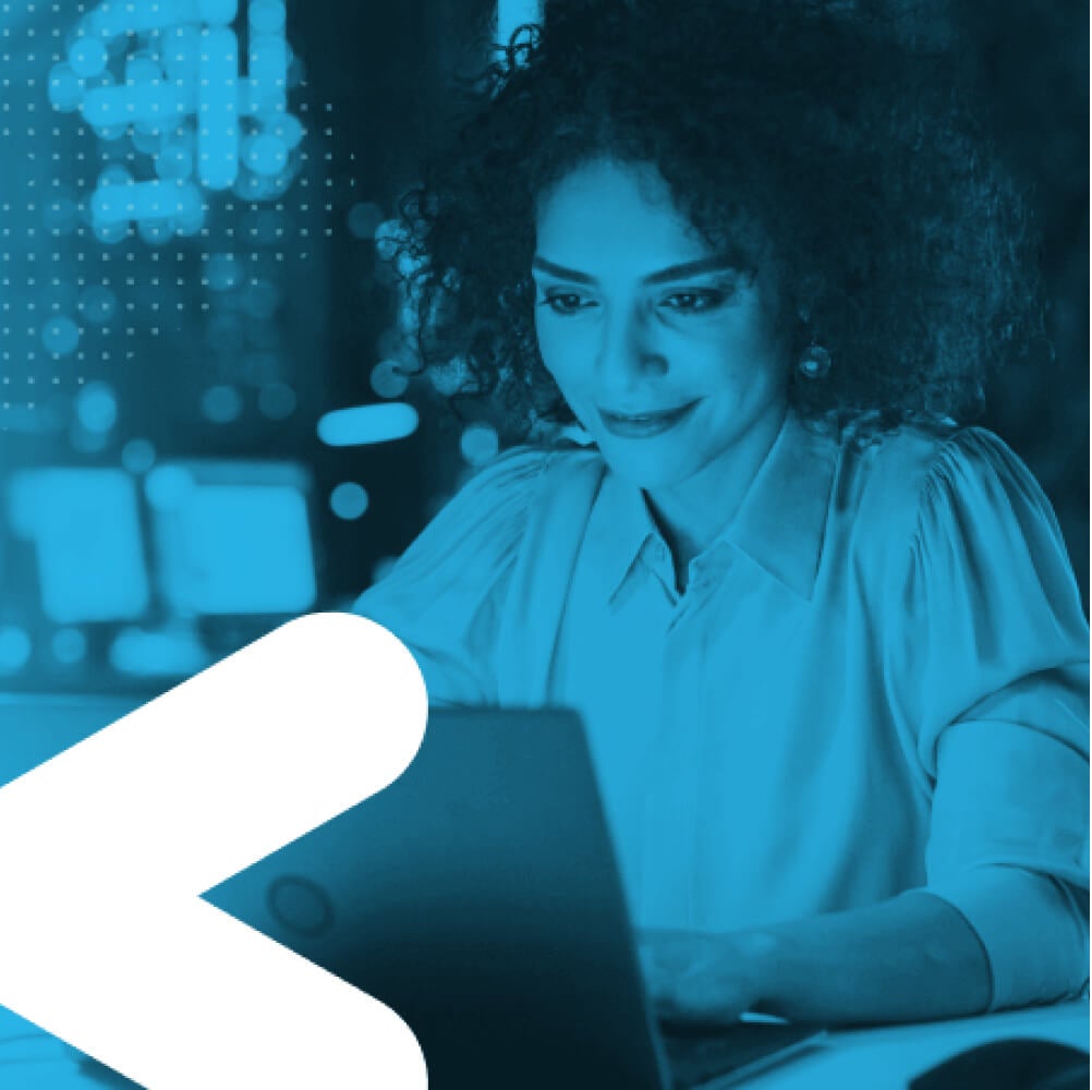 Woman smiling while typing on a laptop in an office