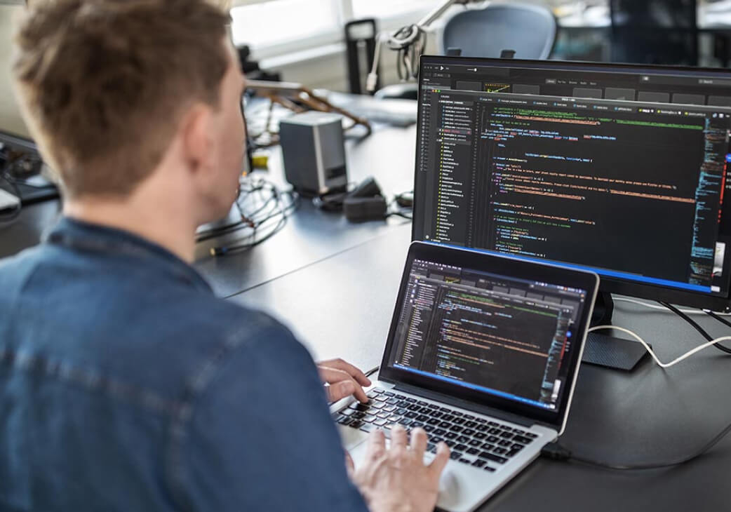 man in front of a laptop showing code