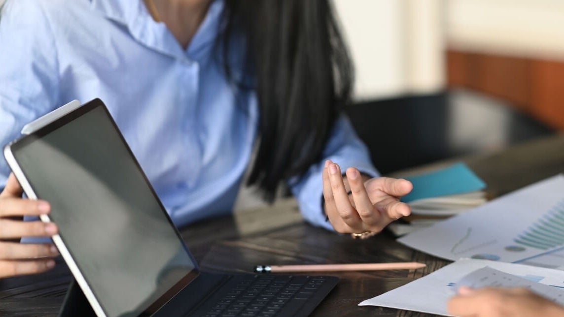 Group of professionals talking at a meeting table around laptops