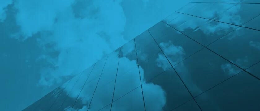 Cloudy day reflecting on office building window; image has a blue overlay