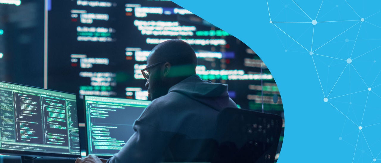 man looks at two monitors