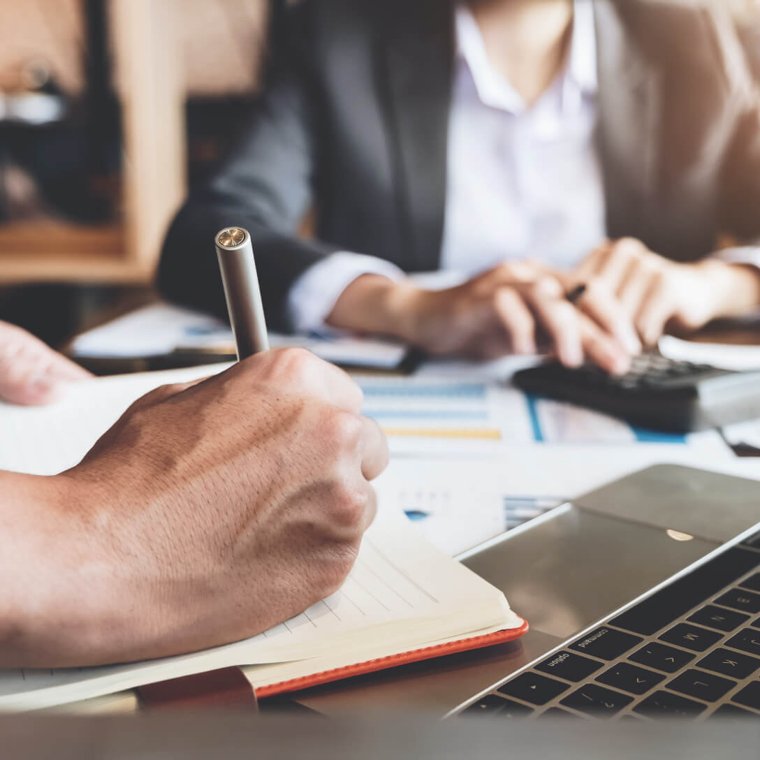 people working together at desk with paperwork and calculator and laptop
