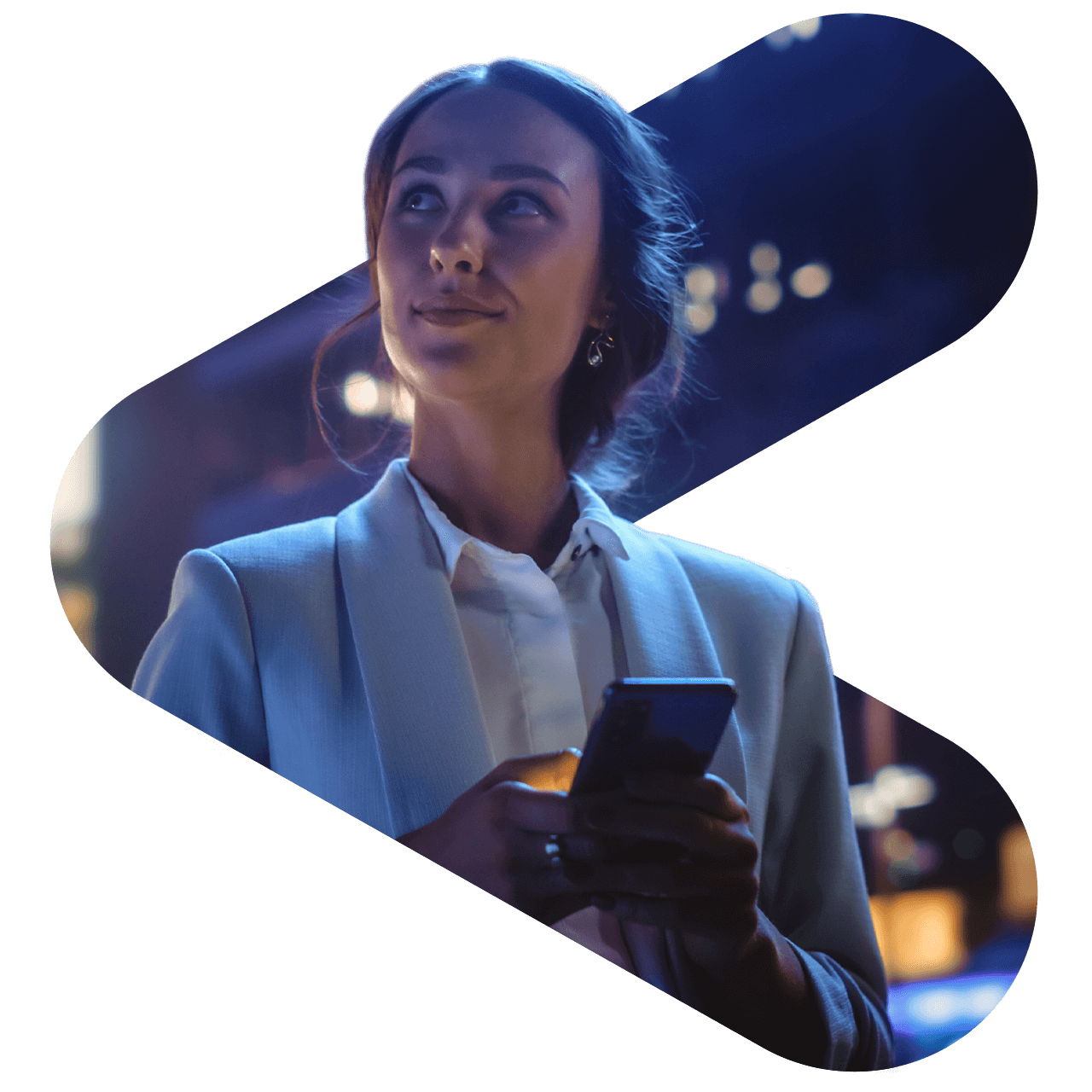 woman holding phone walking on a street at dusk