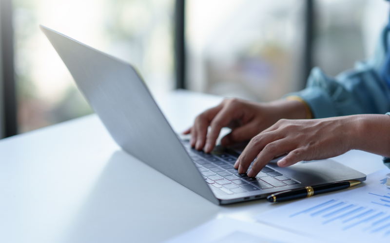 Persons hands typing on a laptop